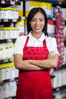 Smiling female staff standing with arms crossed in grocery section