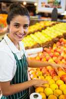 Female staff arranging fruits in organic section of supermarket