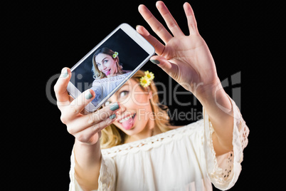 Smiling woman clicking photo from mobile phone against black background