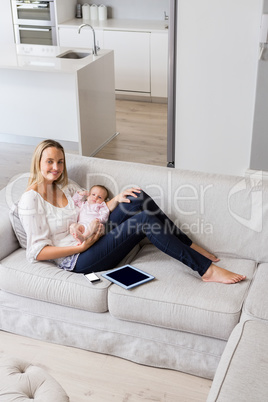 Portrait of smiling mother sitting with her baby in living room