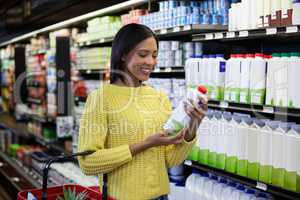 Woman looking milk bottle in dairy section