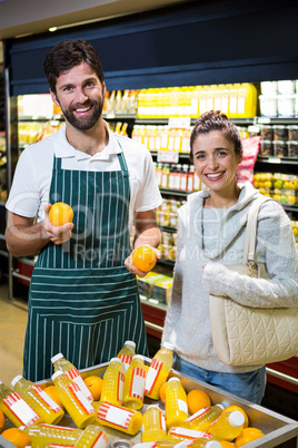 Smiling male staff assisting a woman with grocery shopping