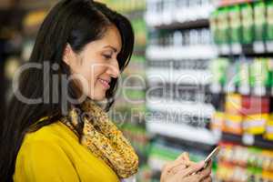 Woman using mobile phone in grocery section