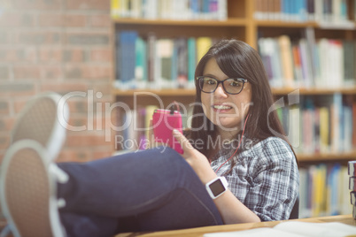 Portrait of female student listening to music on mobile phone