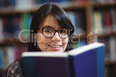 Female student holding book in college library