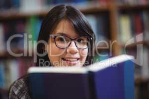 Female student holding book in college library