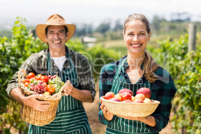 Portrait of happy farmer couple holding baskets of vegetables and fruits