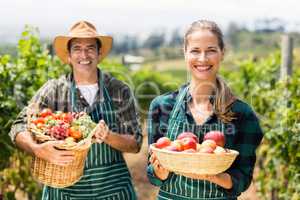 Portrait of happy farmer couple holding baskets of vegetables and fruits