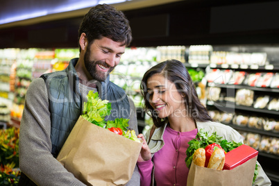 Smiling couple shopping for vegetables in organic section