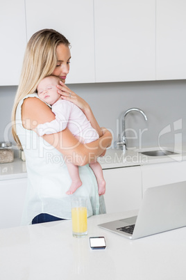 Mother carrying her baby in kitchen