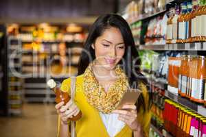 Woman using mobile phone while shopping for grocery