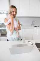 Mother carrying her baby in kitchen