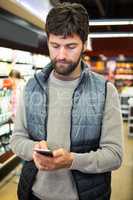 Man using mobile phone in grocery section while shopping