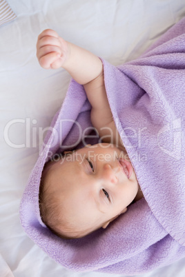 Baby boy relaxing on bed with blanket
