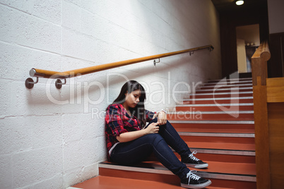 Upset female student sitting on staircase