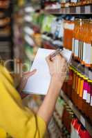 Woman at grocery section writing in notepad