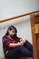 Upset female student sitting on staircase