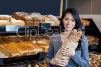 Woman holding baguettes in grocery bag