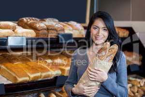 Woman holding baguettes in grocery bag