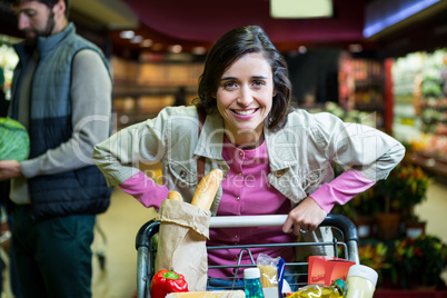 Portrait of smiling woman holding trolley in organic section