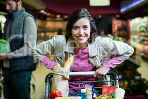 Portrait of smiling woman holding trolley in organic section