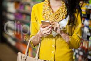 Woman using mobile phone in grocery section