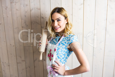 Woman in apron holding a rolling pin against texture background