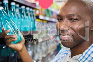 Man looking at bottle of water in supermarket