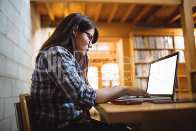 Female student using laptop in library