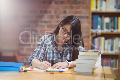 Female student writing notes in library