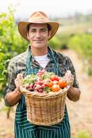 Portrait of happy farmer holding a basket of vegetables