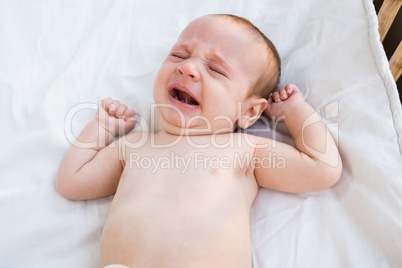 Close-up of crying baby on baby bed