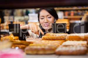 Woman selecting baguettes from bread counter