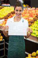 Smiling female staff holding a blank sheet at supermarket