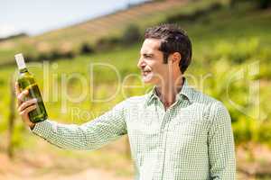 Smiling vintner looking at bottle of wine