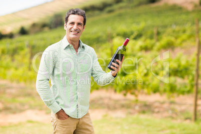 Smiling vintner holding bottle of wine