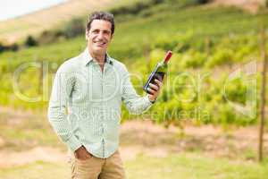 Smiling vintner holding bottle of wine