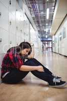 Depressed female student sitting in locker room