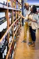 Couple looking at wine bottle in grocery section