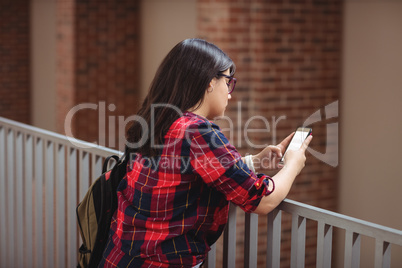 Female student using mobile phone in corridor Female student using mobile phone in corridor