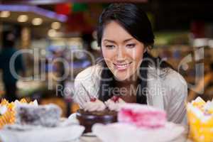 Happy woman selecting desserts from display