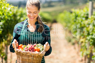 Happy female farmer holding a basket of vegetables
