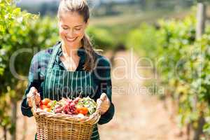 Happy female farmer holding a basket of vegetables