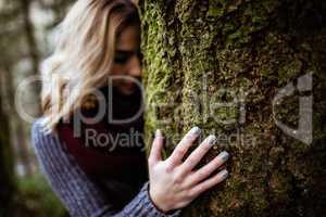 Woman leaning on tree trunk