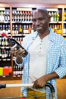 Portrait of man looking at wine bottle in grocery section