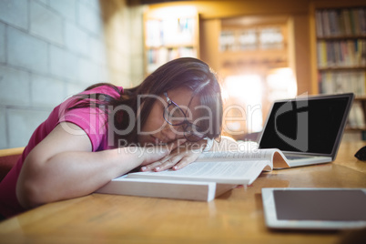 Female student napping on book in library