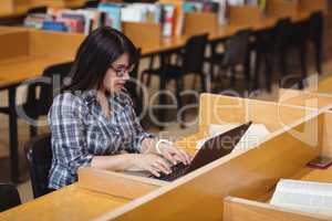 Female student using laptop in library
