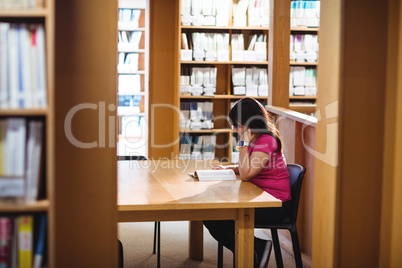 Female student reading book in college library