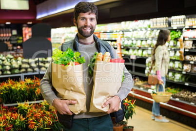 Portrait of smiling man holding a grocery bag in organic section