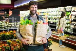 Portrait of smiling man holding a grocery bag in organic section